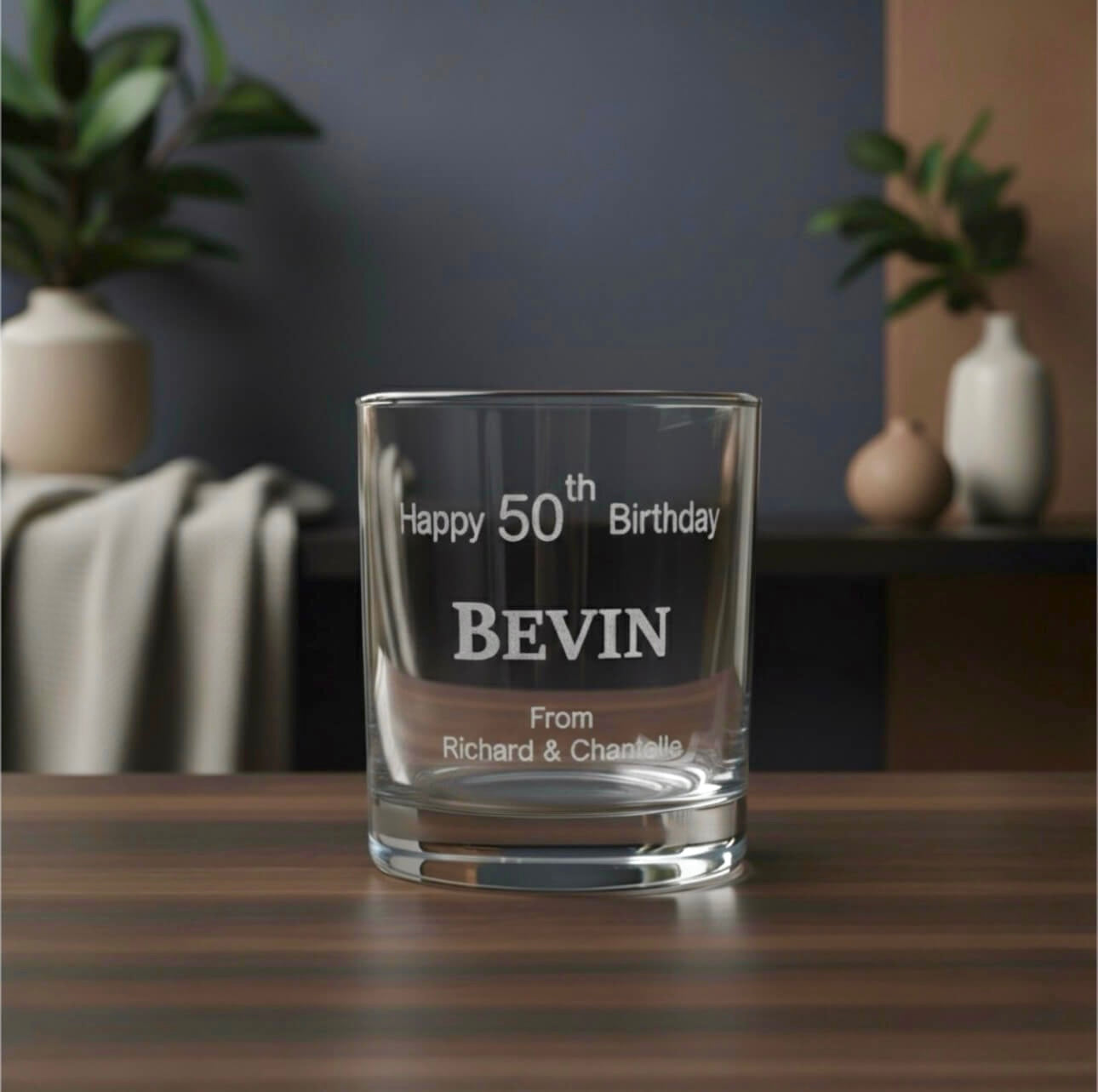 Laser-etched birthday whiskey glass on a wooden surface, featuring a custom name and message.