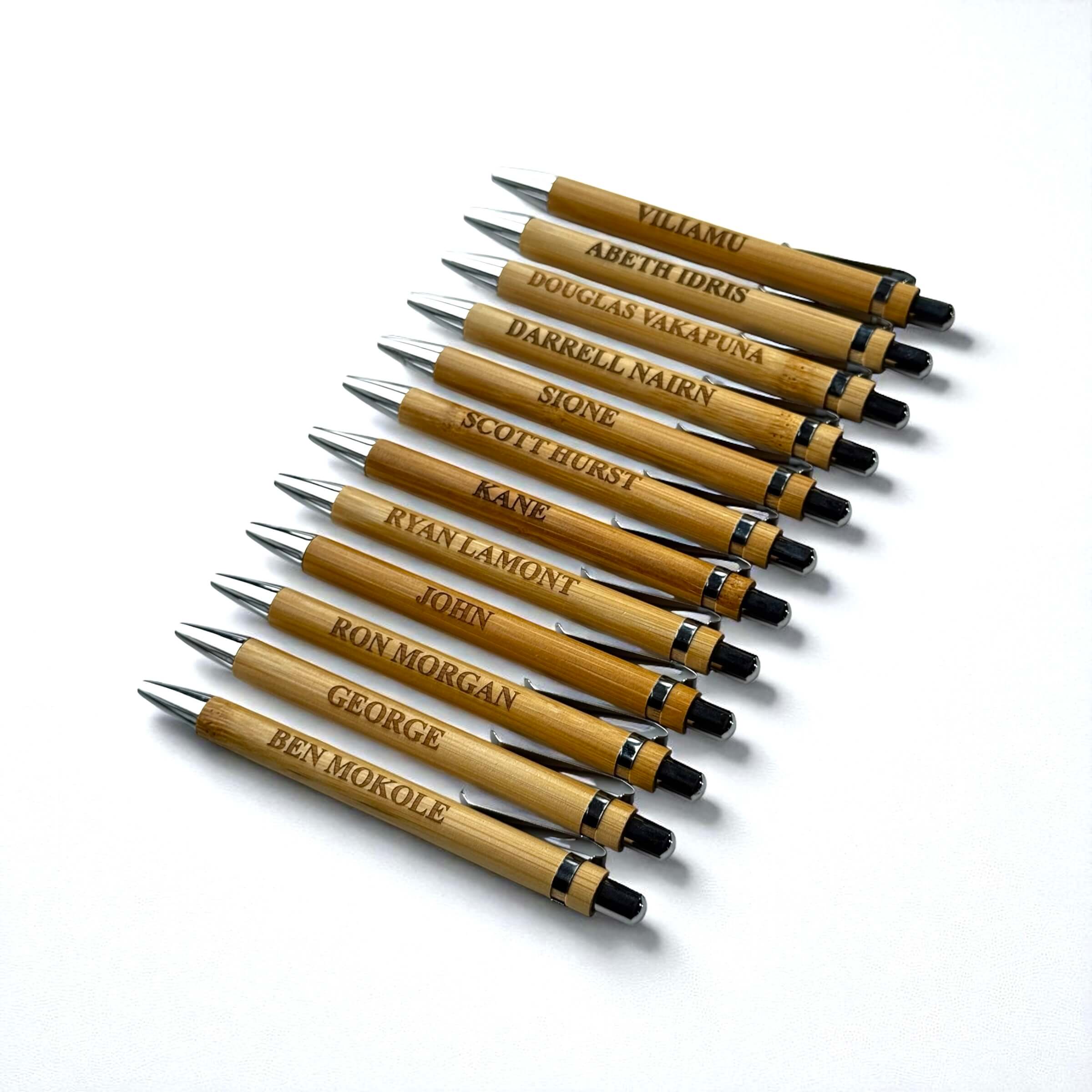 Branded bamboo pens with engraved names, neatly arranged on a white background for business promotions.