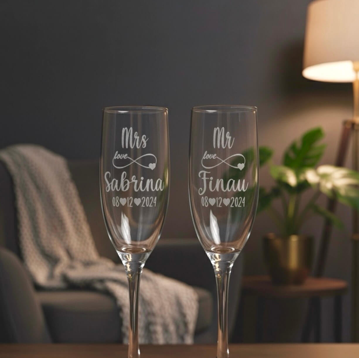 Close-up of custom laser-engraved Mr and Mrs wedding champagne glasses with heart and infinity design.