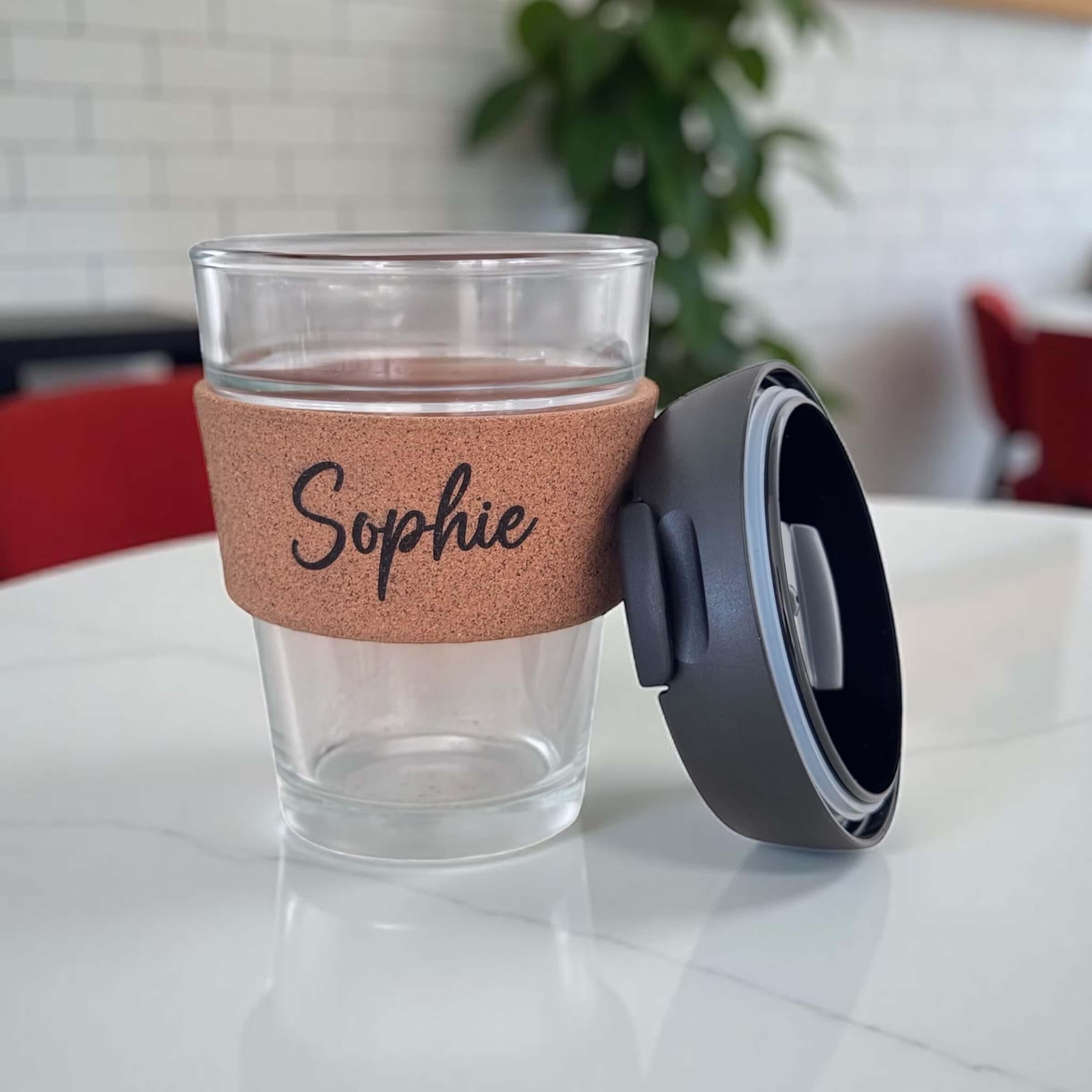 Custom reusable coffee cup with name Sophie and detachable black lid beside the cup