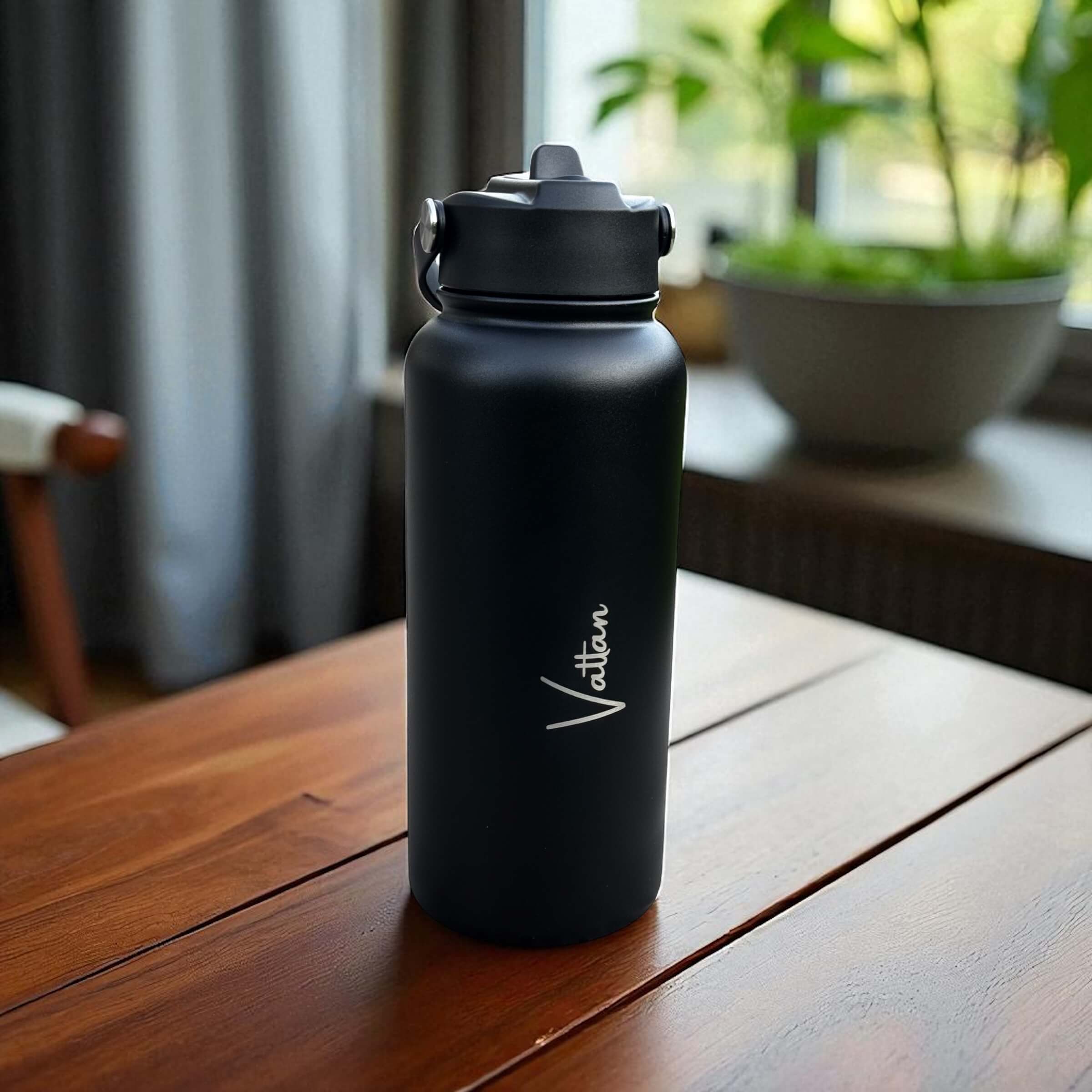 Lifestyle shot of custom engraved water bottle on wooden surface with natural greenery in the background.