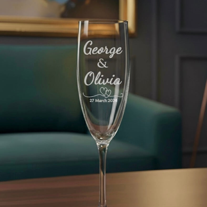 Personalised engraved champagne flute with names George and Olivia and date 27 March 2024 on wooden table