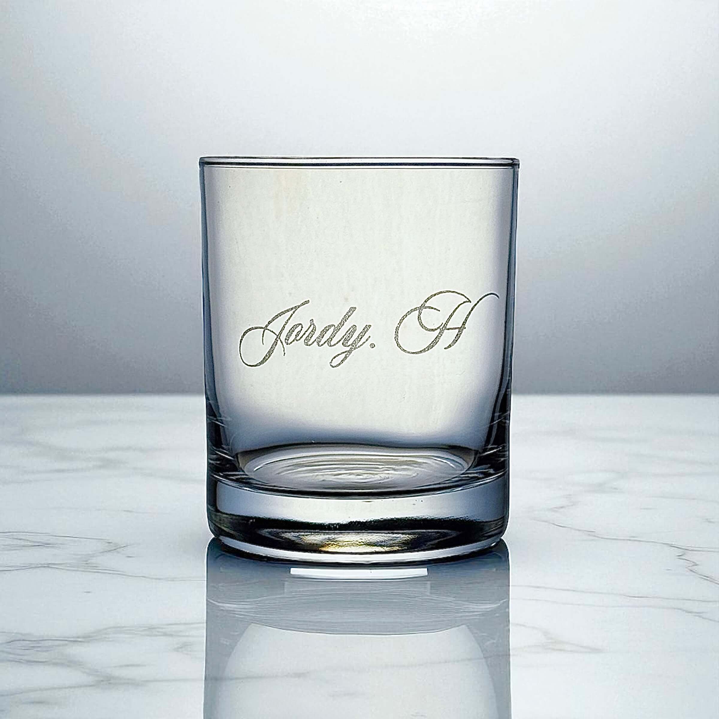Personalised scotch glass engraved with a name, shown on marble surface