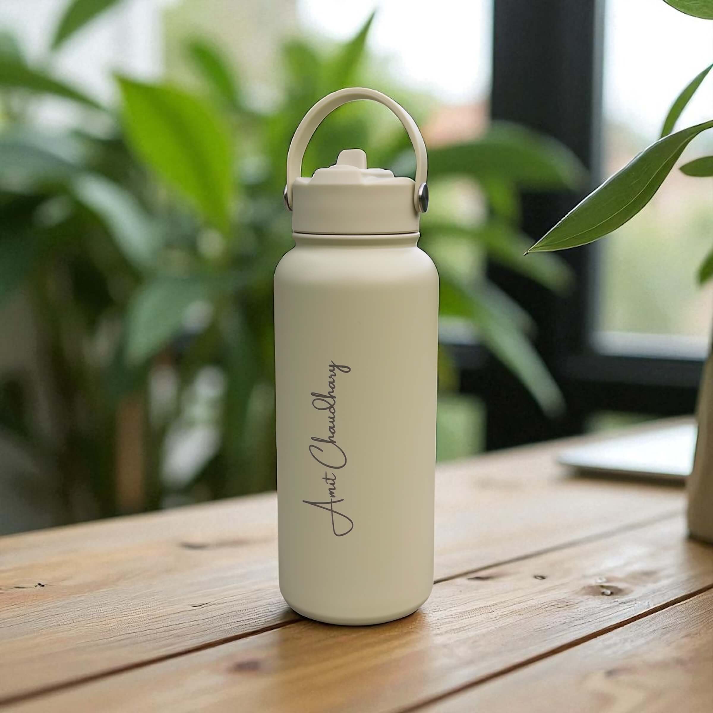 Side angle of personalised sage water bottle with engraved name and straw lid, placed on a wooden tabletop indoors.