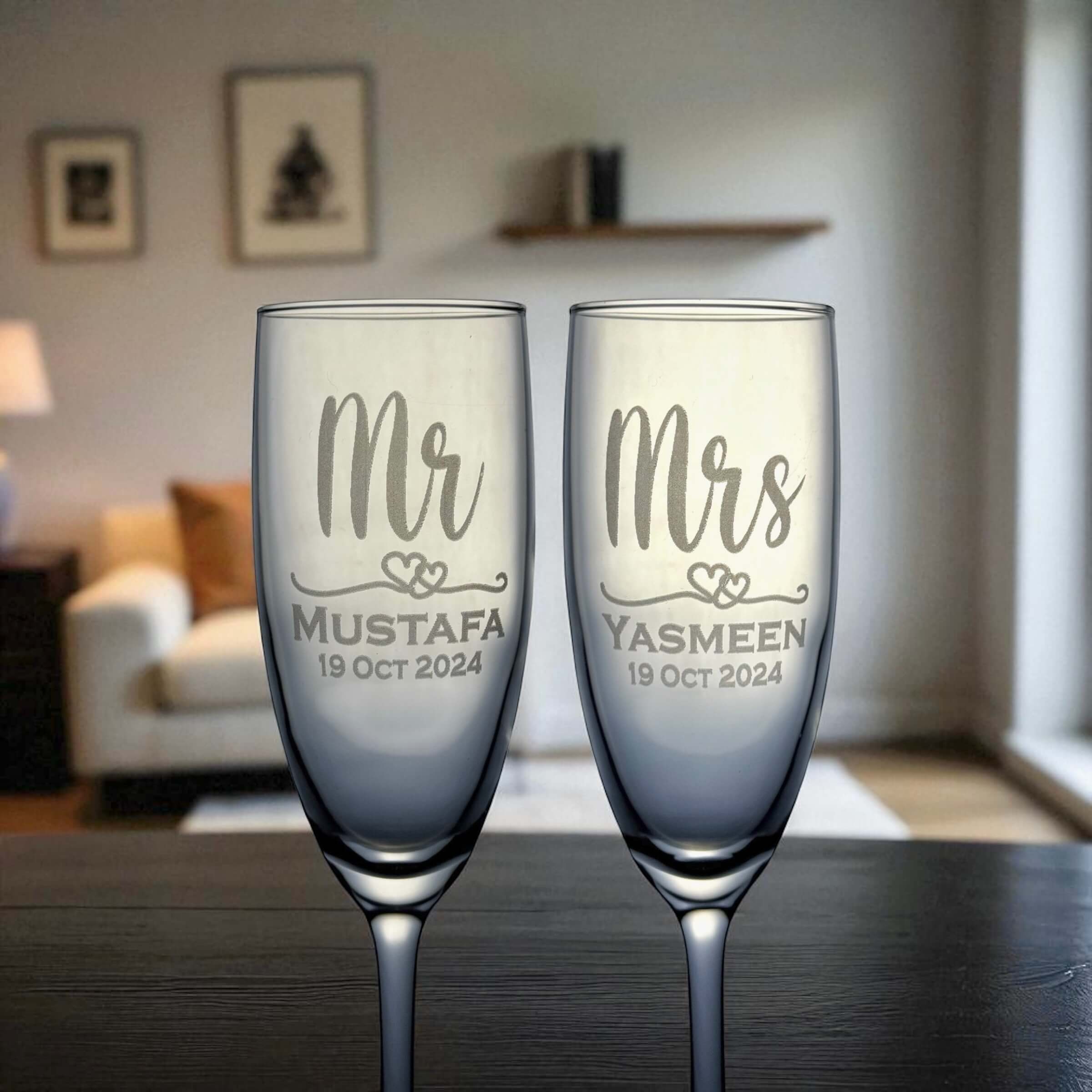 Two personalized champagne flutes with 'Mr' and 'Mrs' engraved on a table.