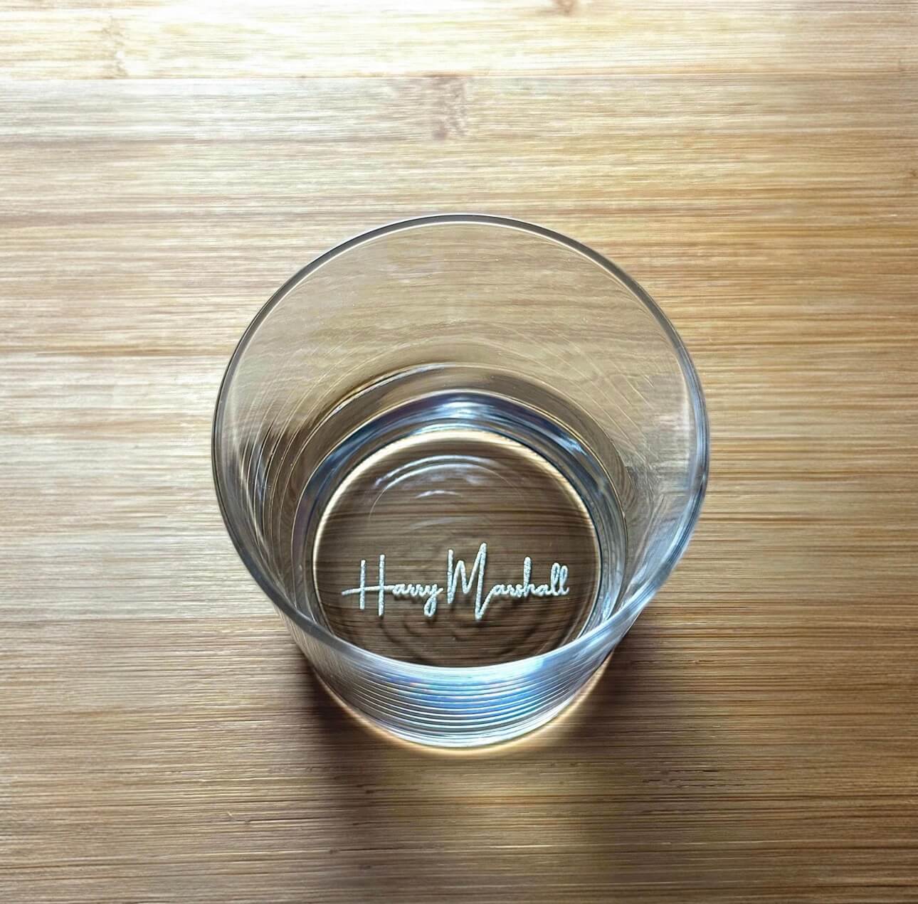 Whiskey glass placed on wooden surface personalised with name.