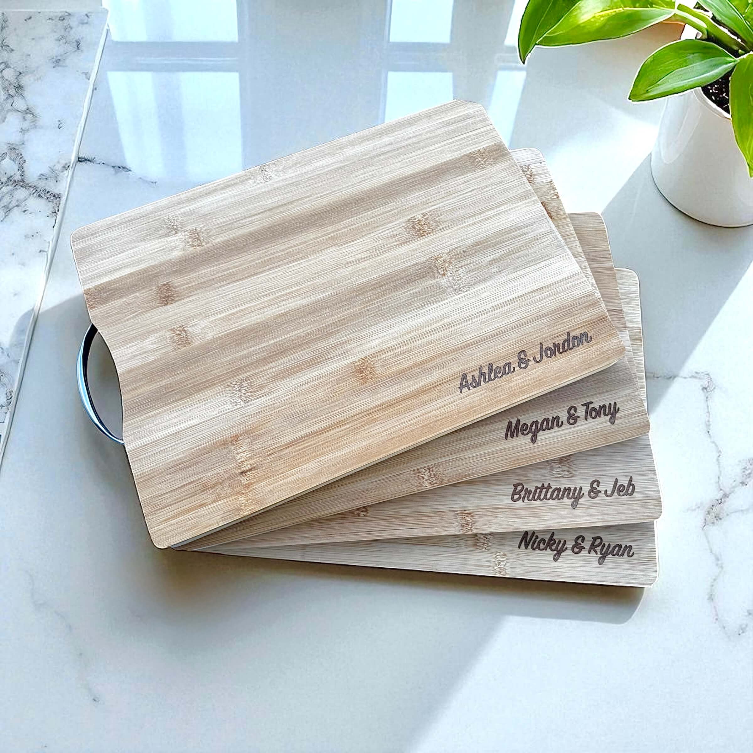 Stack of personalised bamboo chopping boards engraved with names.