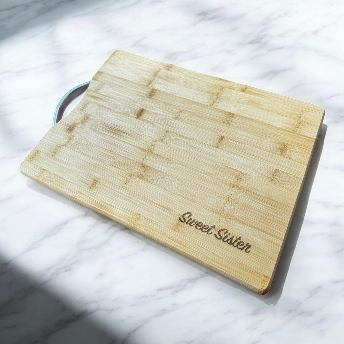 Personalised bamboo chopping board with Stainless steel handle and engraved text, angled view showing full size