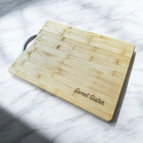 Personalised bamboo chopping board with Stainless steel handle and engraved text, angled view showing full size