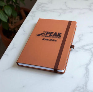 A5 leather journal with elastic closure engraved with company branding.