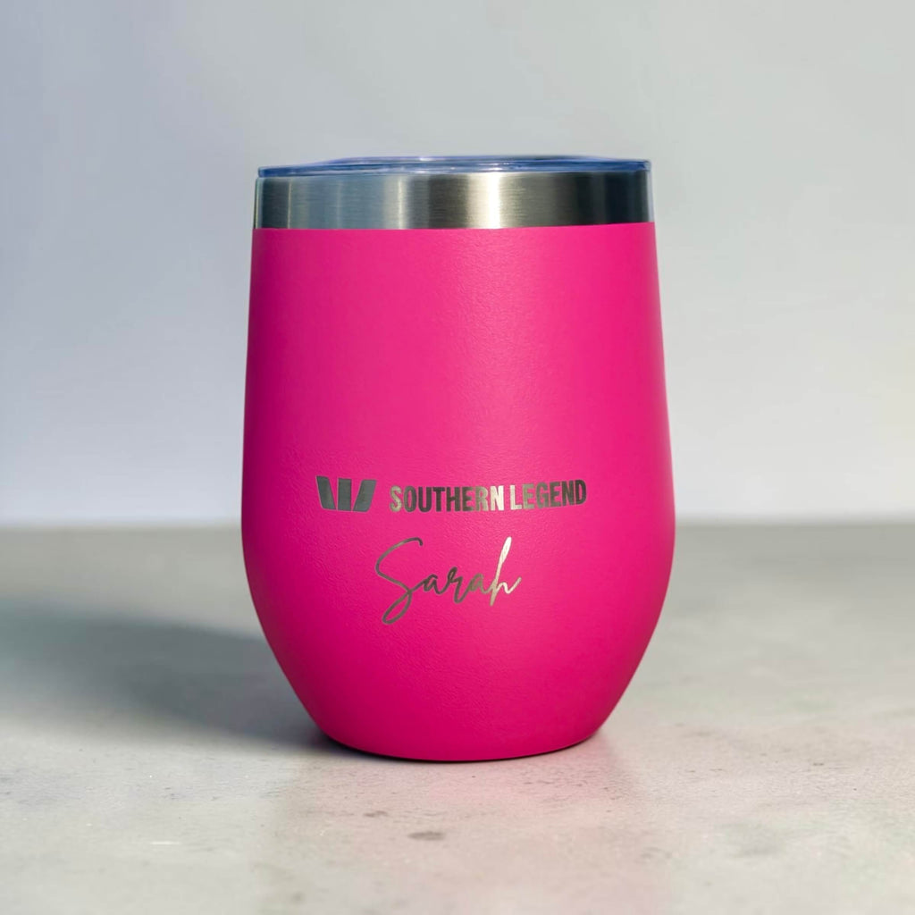 A bright pink insulated stemless tumbler with a brushed stainless steel rim and a clear lid, featuring the engraved text 'SOUTHEEN LEGEND' and the name 'Sarah' in silver on the front, set against a neutral grey background.
