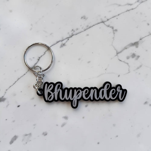 Acrylic keychain with 'Bhupender' text on a marble surface