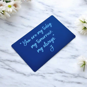 Angled black wallet insert card showing engraved message on white marble surface