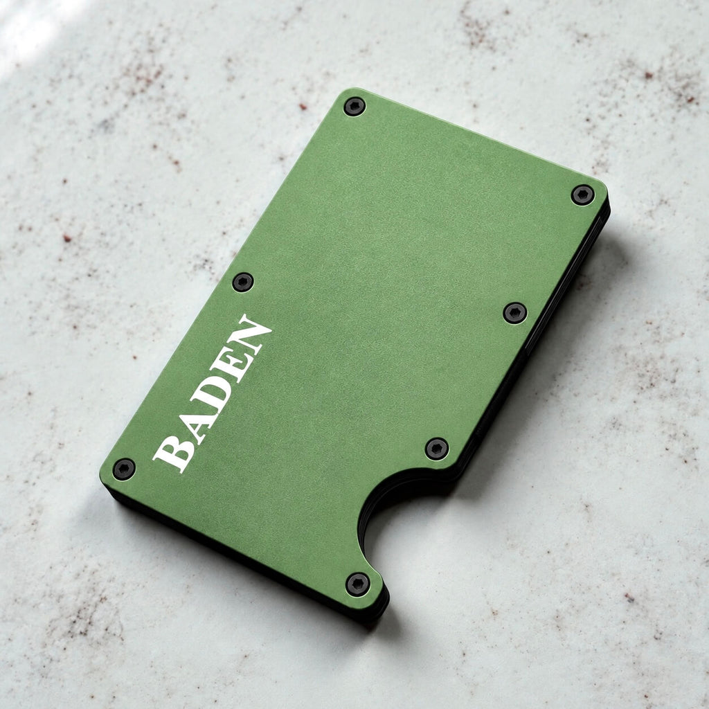Angled view of a personalised green metal card holder with engraved name on a marble surface