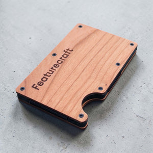 Angled view of a personalised wooden card holder showing engraved branding and slim profile