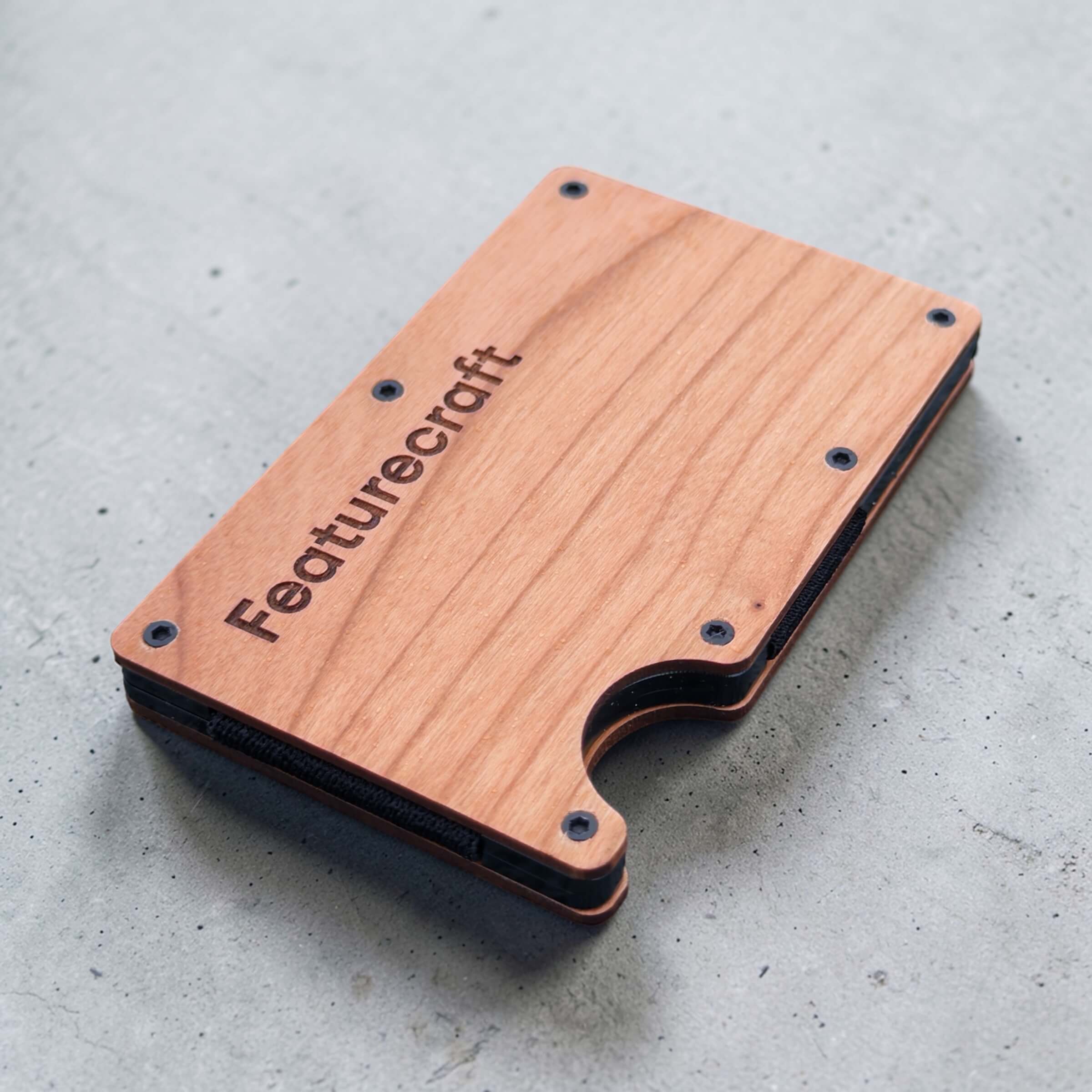 Angled view of a personalised wooden card holder showing engraved branding and slim profile
