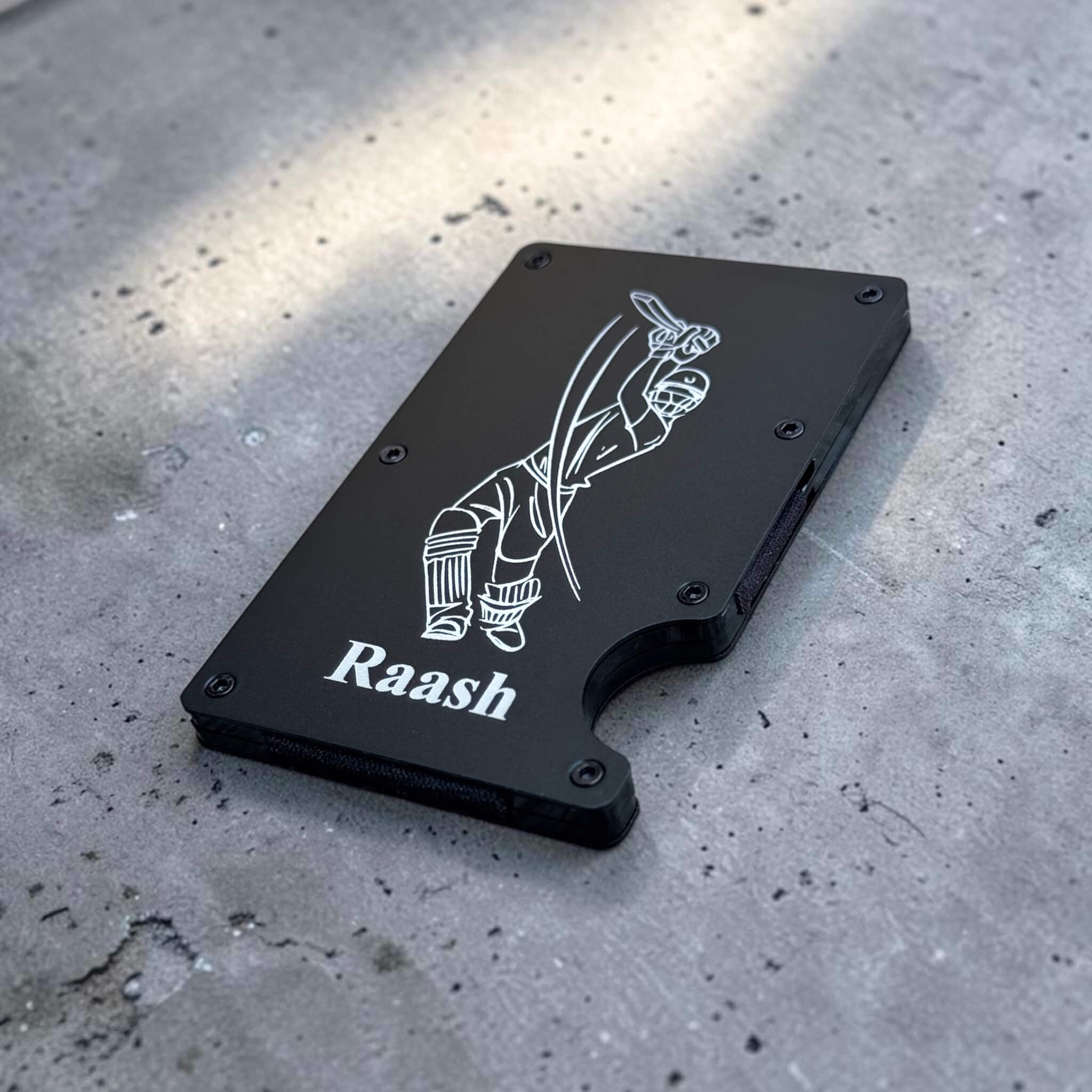 Angled view of personalised metal wallet with engraved design on a matte black finish