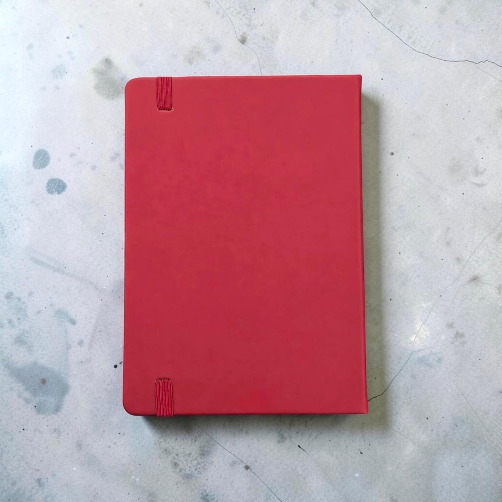 Back view of a maroon PU leather A5 notebook with a matching Maroon elastic closure tab, placed on a light gray concrete surface.