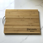 Bamboo chopping board engraved with company logo and name, styled on a marble kitchen bench.