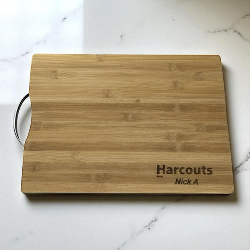 Bamboo chopping board engraved with company logo and name, styled on a marble kitchen bench.