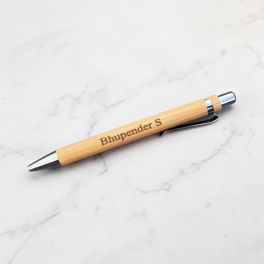 Bamboo pen with engraved name on a marble surface