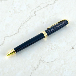 Black and gold engraved anniversary pen shown on a light marble-style surface as a custom couple gift