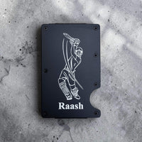 Black custom engraved metal card holder with personalised design and 'Raash' text on a gray concrete surface