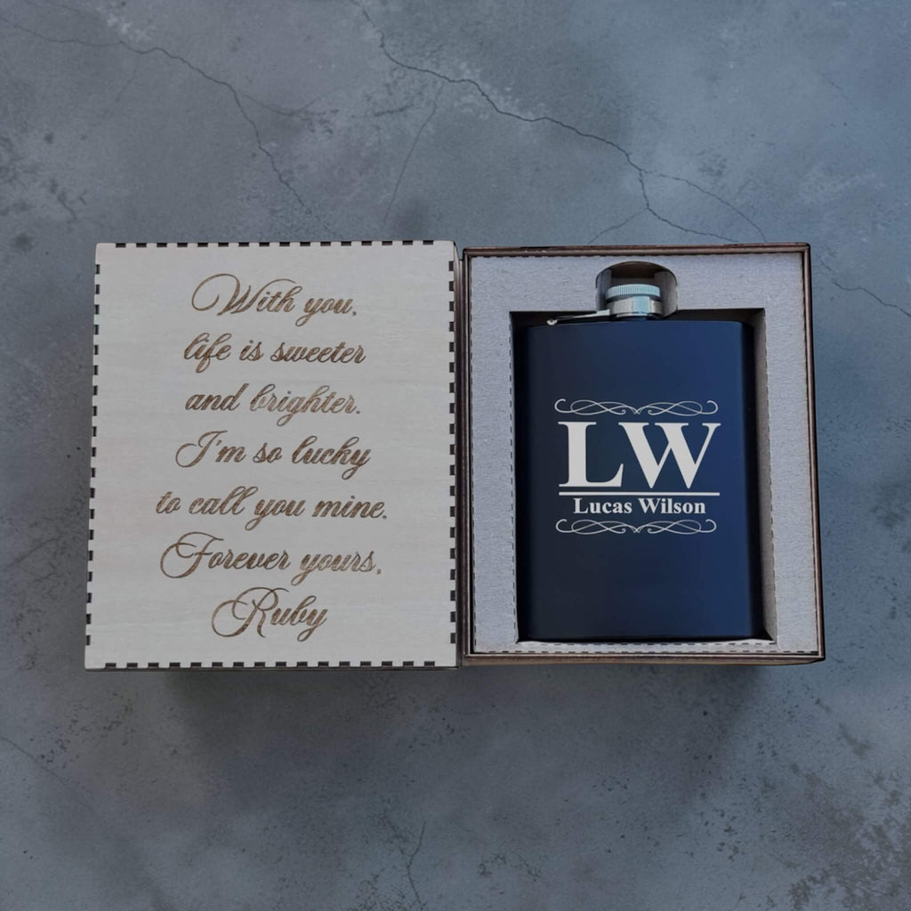 Black flask with 'LW Lucas Wilson' engraving in a box with a sentimental message on a gray background