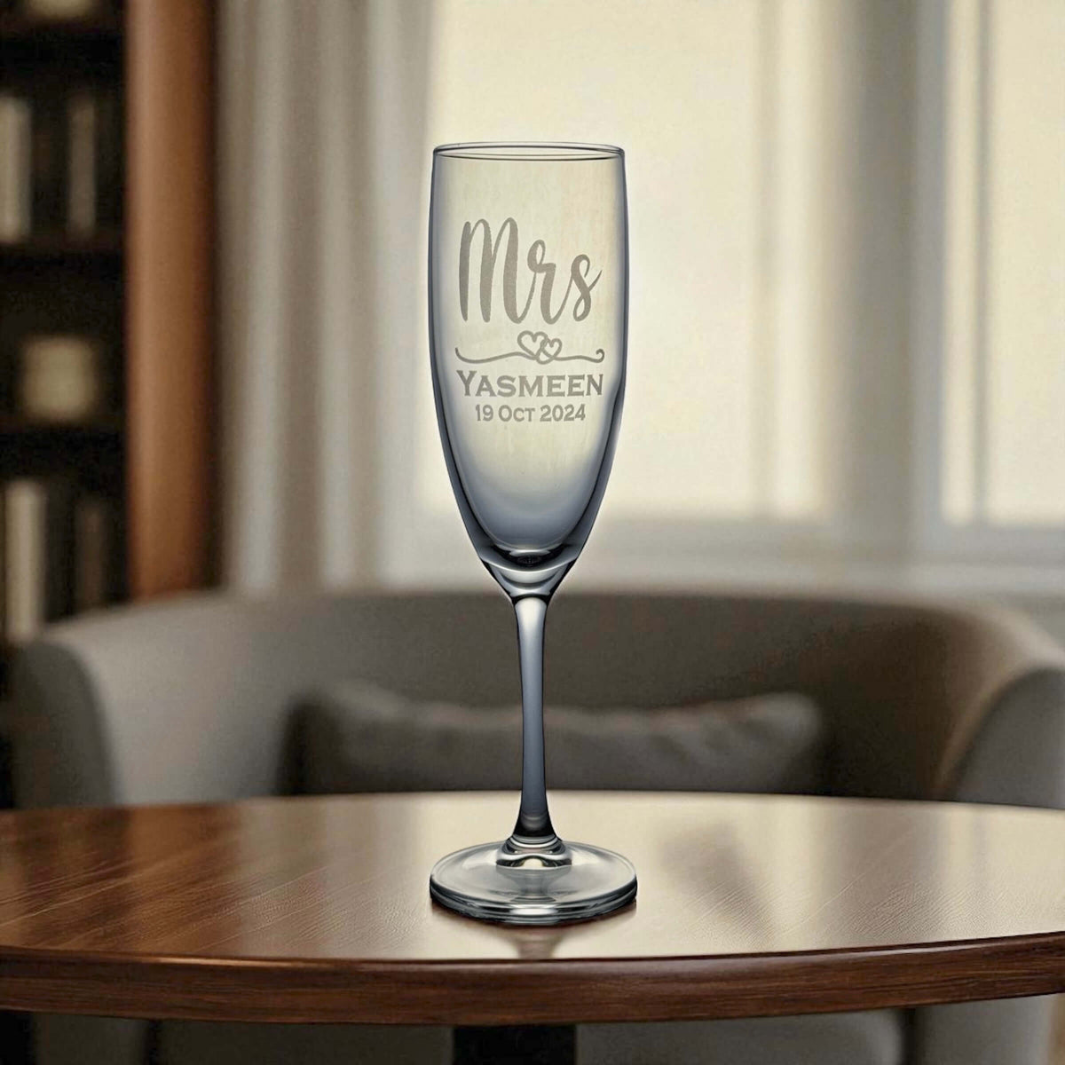 Champagne glass with 'Mrs' and personalized text on a wooden table.