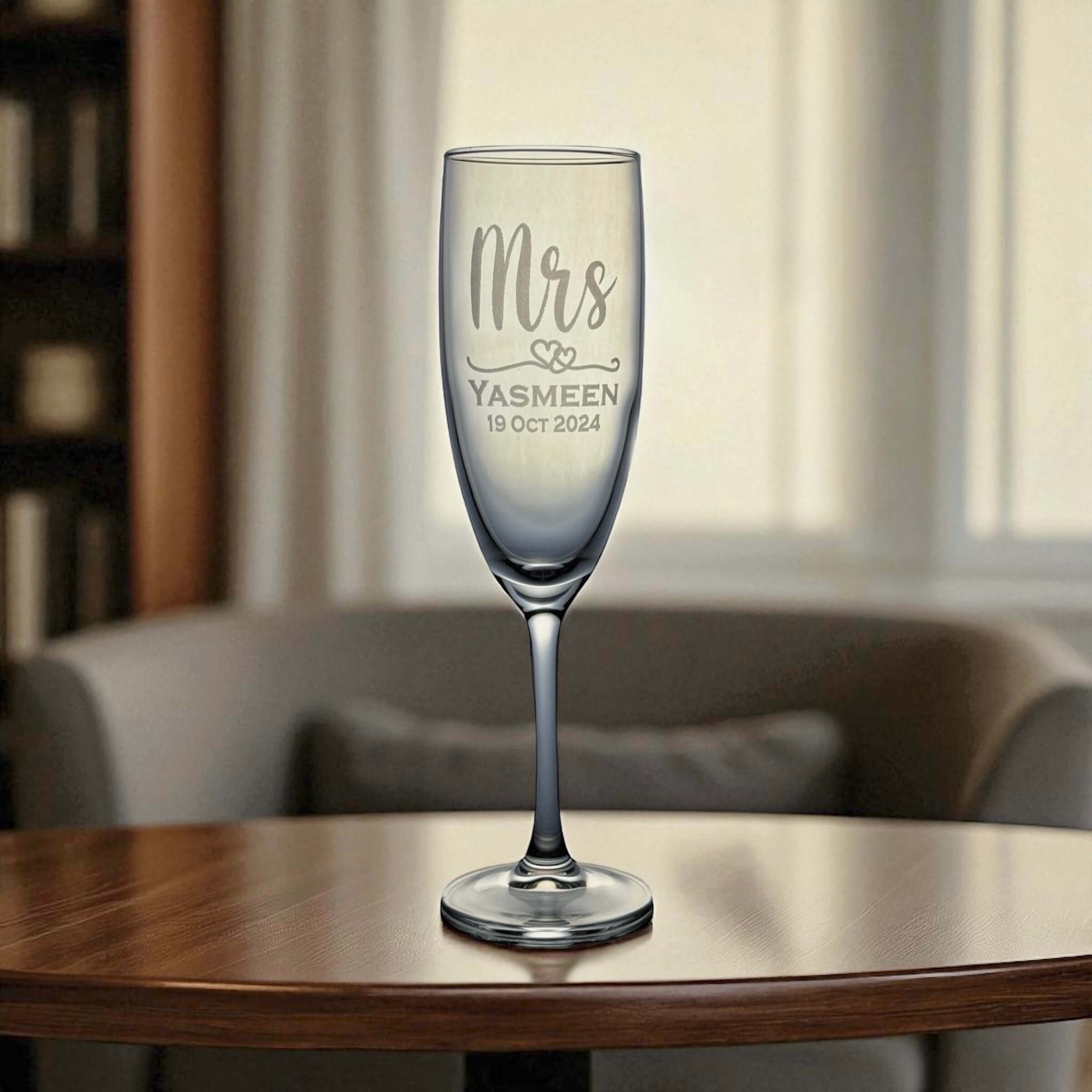 Champagne glass with 'Mrs' and personalized text on a wooden table.