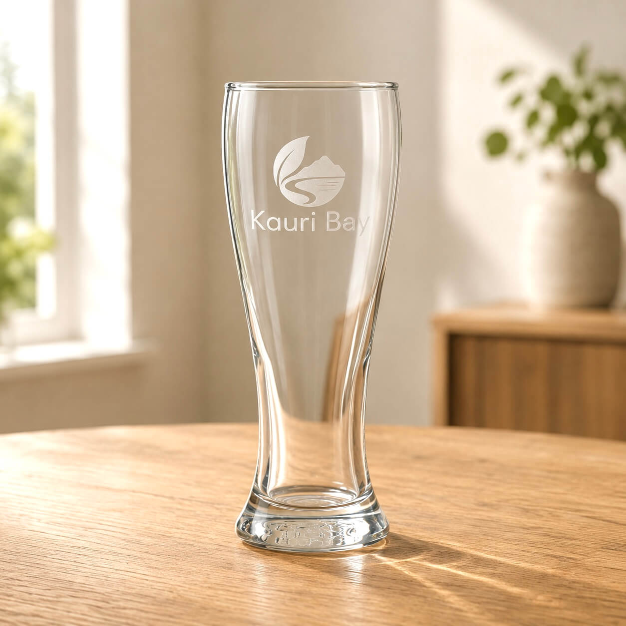 Clear corporate beer glass with Kauri Bay logo engraved on the front