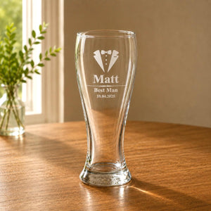 Clear engraved pint glass for a groomsman gift beside a bright window