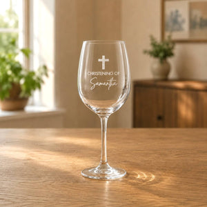 Clear engraved wine glass with christening cross design in a warm home setting