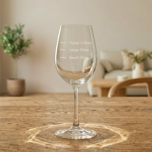 Clear engraved wine glass with playful size lines in a warm lounge setting