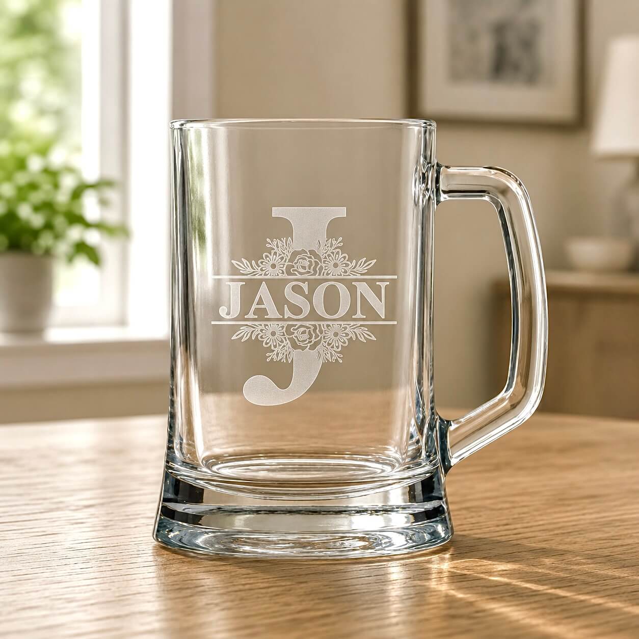 Clear glass beer mug with engraved Jason split monogram and floral detail on wooden table