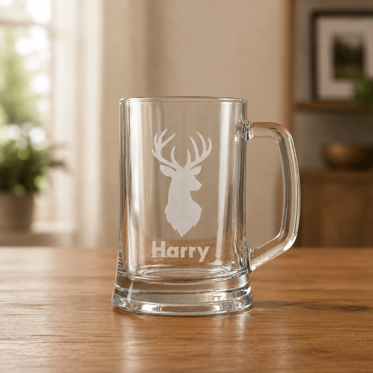 Clear glass beer mug with white stag engraving and the name Harry on a wooden table