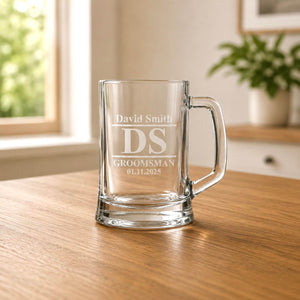 Clear glass beer tankard with etched groomsman design and David Smith name in warm home setting