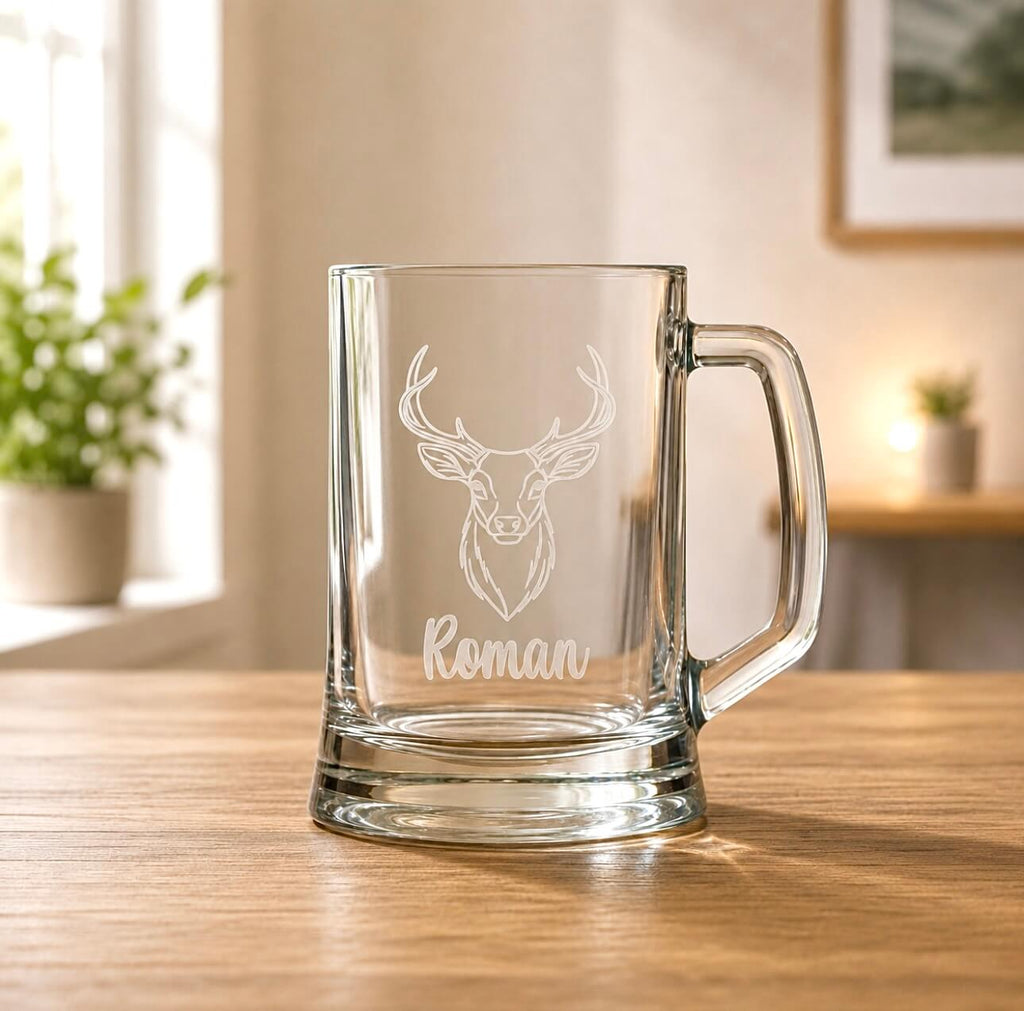 Clear glass beer tankard with etched stag design and Roman name in warm home setting