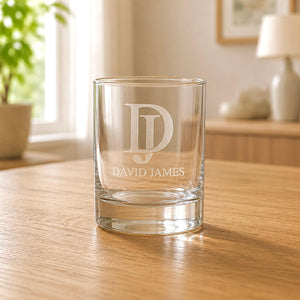 Clear glass tumbler with 'David James' engraving on a wooden table.