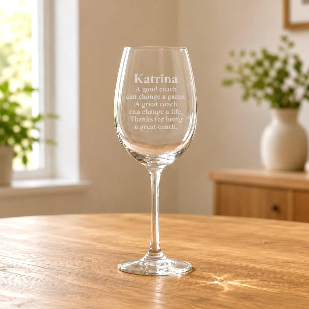 Clear stemmed wine glass with frosted coach message engraving on wooden table