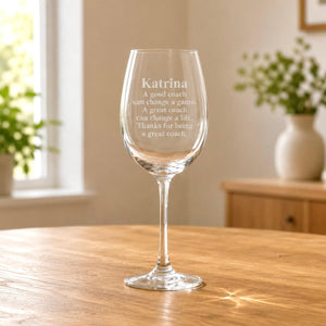 Clear stemmed wine glass with frosted coach message engraving on wooden table