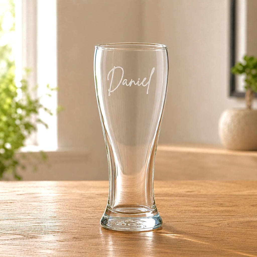 Clear tall beer glass with 'Daniel' engraving on a wooden table