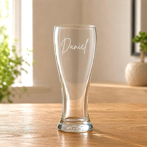 Clear tall beer glass with 'Daniel' engraving on a wooden table