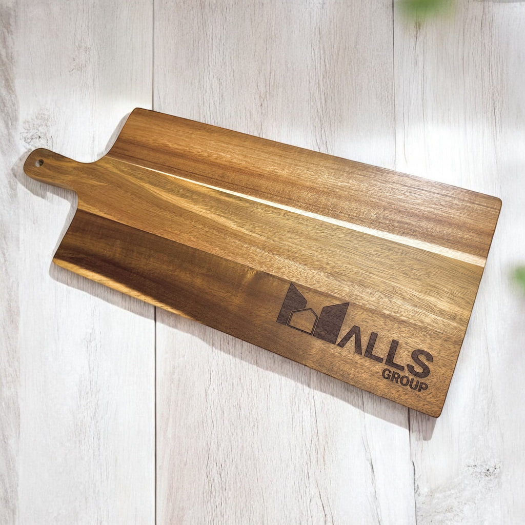 Close-up of acacia serving board engraved with company logo on light wooden surface