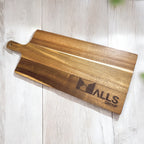 Close-up of acacia serving board engraved with company logo on light wooden surface