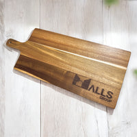Close-up of acacia serving board engraved with company logo on light wooden surface