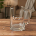 Close-up of clear glass beer mug with engraved name George, personalised glass gift on rustic wooden surface