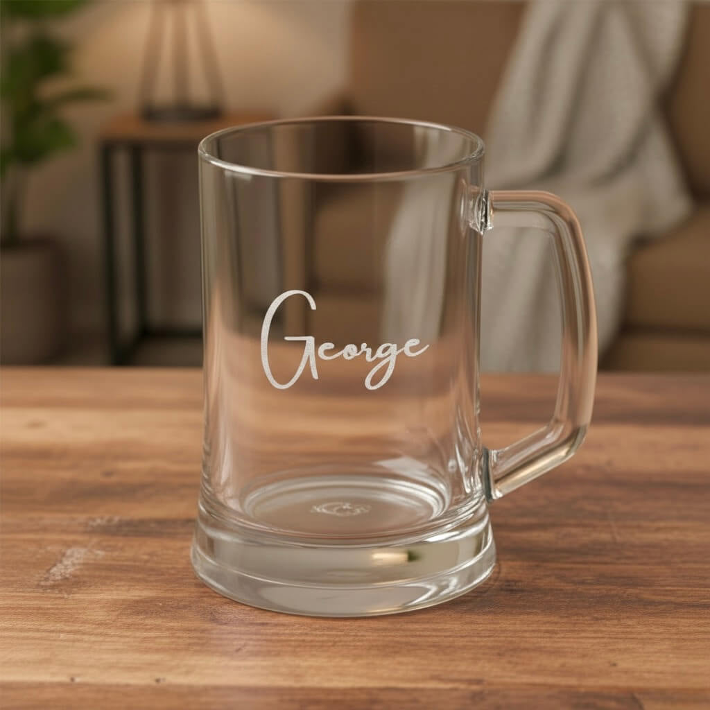 Close-up of clear glass beer mug with engraved name George, personalised glass gift on rustic wooden surface