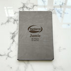 Close-up of custom laser-engraved hardcover notebook showing logo, name, and milestone years of service, perfect for staff recognition gifts.