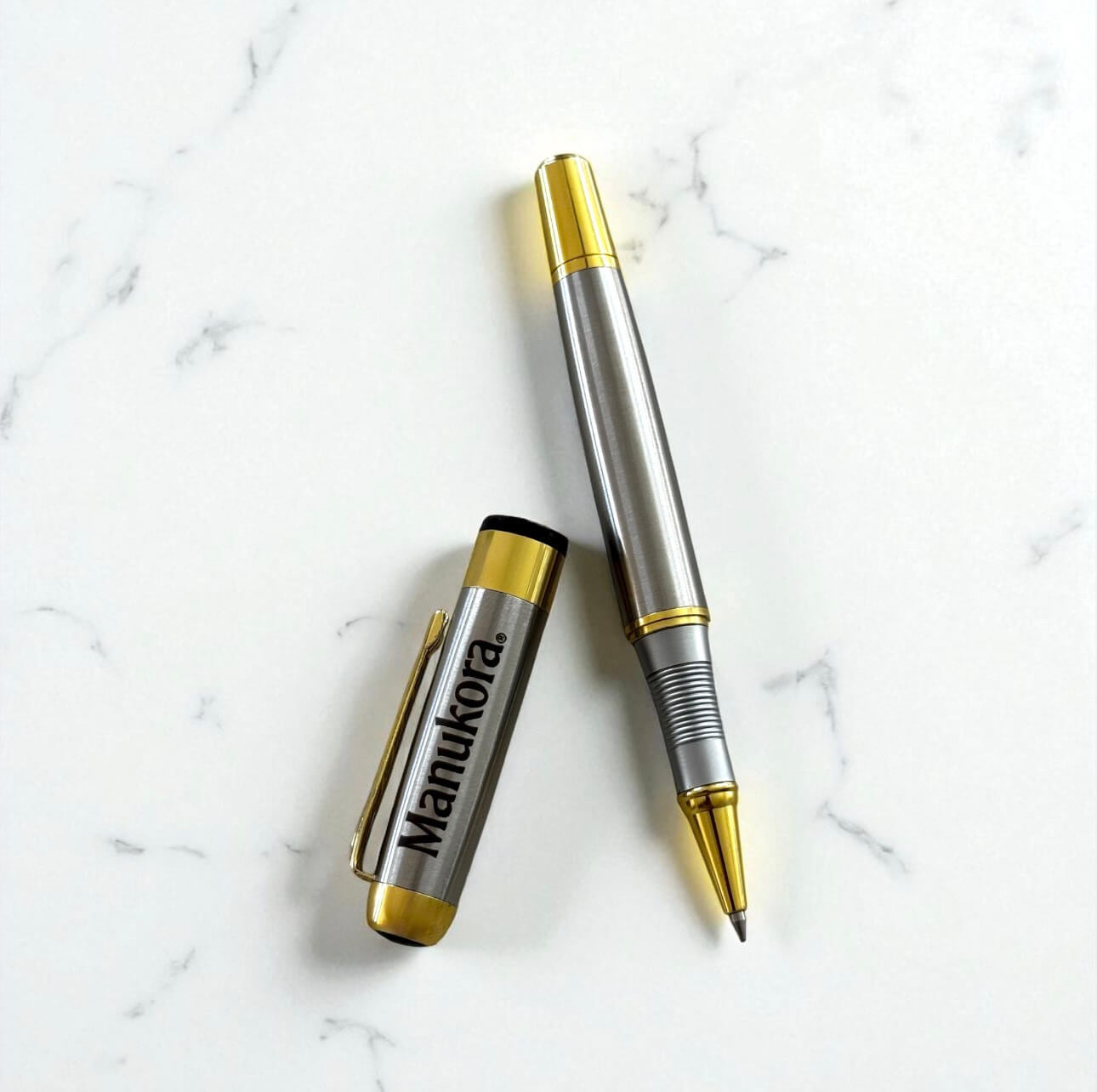 Close-up of engraved cap and open pen, highlighting logo detail and premium finish.